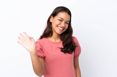 Genç Kolombiyalı kız izole edilmiş beyaz arka planda mutlu bir ifadeyle selamlıyor.