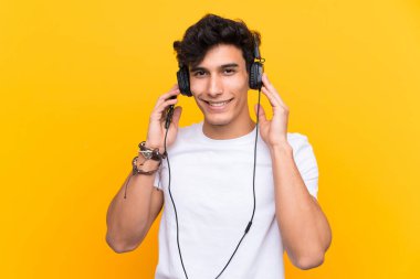 Arjantinli genç adam, izole edilmiş sarı bir duvarın üzerinde gezici bir araçla müzik dinliyor.
