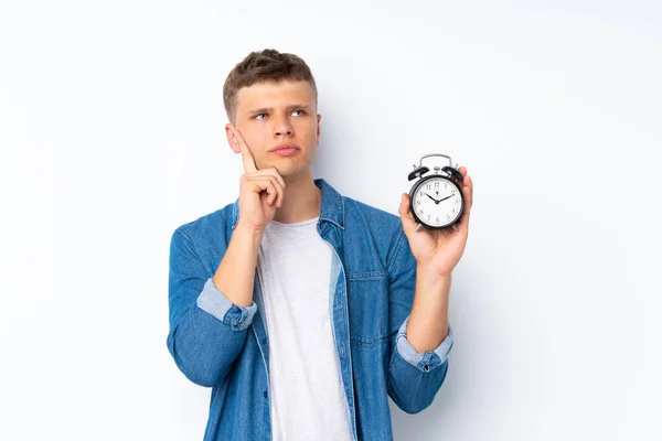 Ung Stilig Man Över Isolerad Vit Bakgrund Håller Vintage Väckarklocka — Stockfoto