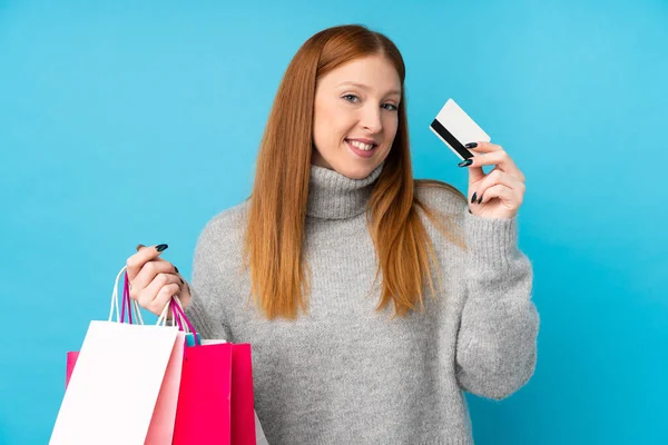 Ung Rödhårig Kvinna Över Isolerad Blå Bakgrund Håller Shoppingväskor Och — Stockfoto