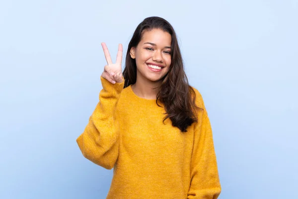 Joven Colombiana Con Suéter Sobre Fondo Azul Aislado Sonriendo Mostrando —  Fotos de Stock
