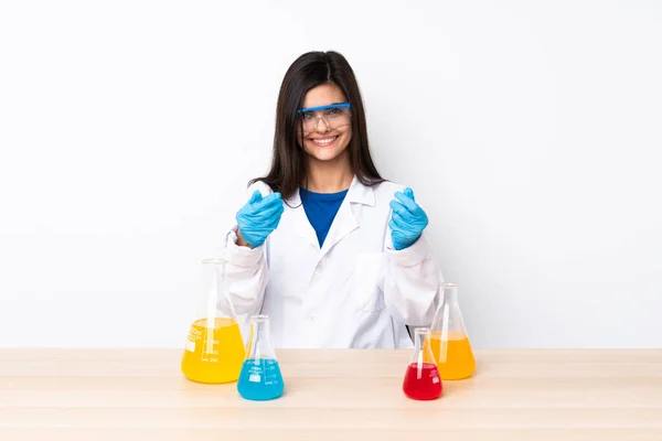 一个年轻的科学女人坐在桌子上做着赚钱的姿势 — 图库照片