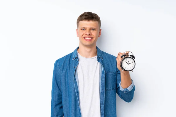 Joven Hombre Guapo Sobre Fondo Blanco Aislado Sosteniendo Reloj Despertador — Foto de Stock