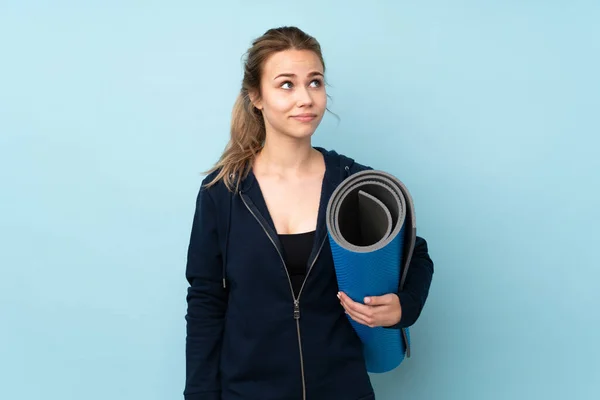 Adolescente Russo Menina Segurando Tapete Isolado Fundo Azul Fazendo Dúvidas — Fotografia de Stock