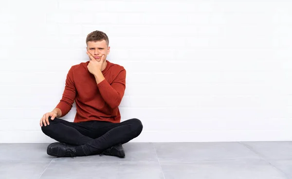 Mladý Pohledný Muž Sedící Podlaze Přemýšlející — Stock fotografie