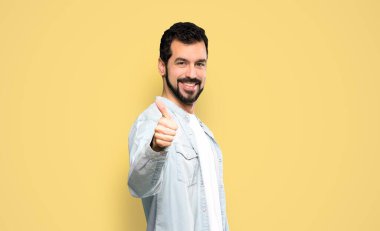 Sakallı ve sakallı yakışıklı bir adam. Çünkü izole edilmiş sarı arka planda iyi bir şey oldu.