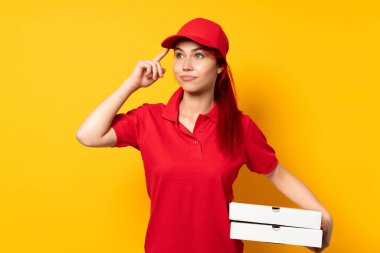 Pizza teslimatçısı kız izole edilmiş arka planda pizza tutuyor. Şüpheleri var ve düşünüyor.