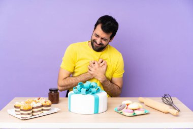 Büyük bir pastayla masada oturan adamın yüreği sızlıyor.