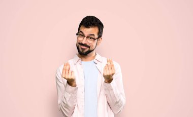 Sakallı yakışıklı adam soyutlanmış pembe arka planda para yapıyor.