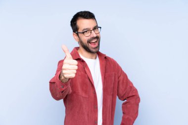 Mavi arka planda kadife ceket giyen beyaz bir genç. Başparmakları havada. Çünkü iyi bir şey oldu.