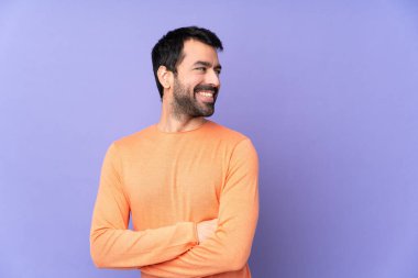 Kolları çapraz ve mutlu bir şekilde izole edilmiş, mor bir geçmişi olan beyaz yakışıklı bir adam.