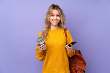 Mor arka planda izole edilmiş genç bir Rus öğrenci. Elinde kahve ve cep telefonu var.