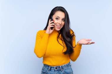 İzole edilmiş mavi geçmişi olan genç Kolombiyalı bir kız cep telefonuyla sohbet ediyor.