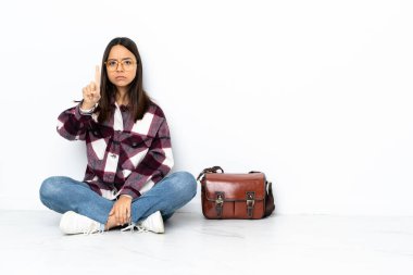 Yerde oturan genç bayan öğrenci ciddi bir ifadeyle sayıyor.