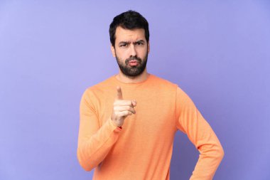 Kafkasyalı yakışıklı adam mor arka planda hayal kırıklığına uğramış ve ön tarafı işaret ediyor.