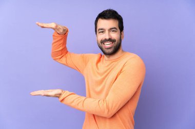 İzole edilmiş mor arka planda beyaz yakışıklı bir adam bir ilan vermek için kopyalama alanı tutuyor.