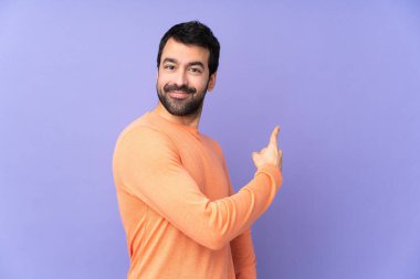 Kafkas yakışıklı adam izole edilmiş mor arka plan geriye işaret ediyor.