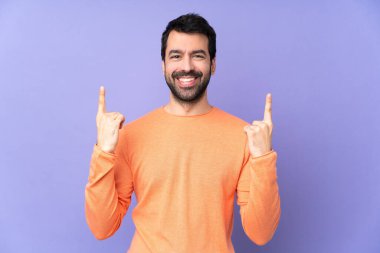İzole edilmiş mor arka planı olan beyaz, yakışıklı bir adam harika bir fikre işaret ediyor.