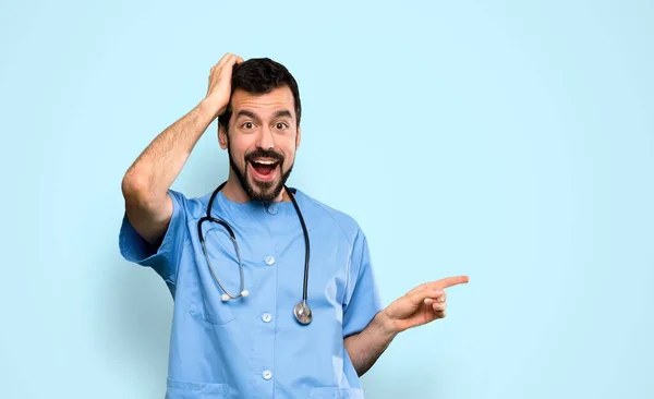 Cirujano Médico Hombre Sorprendido Señalando Dedo Lado Sobre Fondo Azul — Foto de Stock