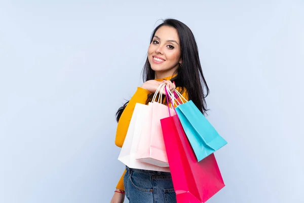 Joven Colombiana Sobre Fondo Azul Aislado Sosteniendo Bolsas Compras Sonriendo —  Fotos de Stock