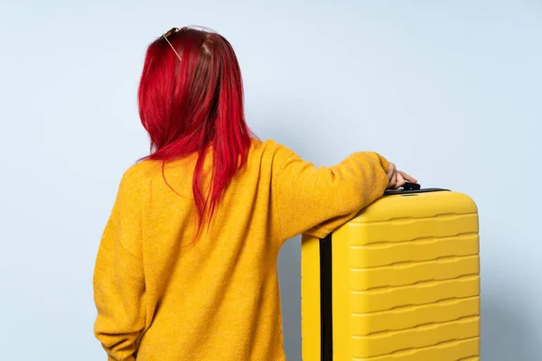 旅行女孩背着一个蓝色背景的手提箱 背对着旁边看 — 图库照片