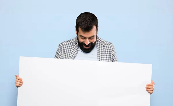 Bonito Homem Com Barba Segurando Cartaz Vazio Sobre Fundo Azul — Fotografia de Stock