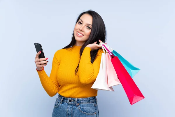 Joven Colombiana Sobre Fondo Azul Aislado Sosteniendo Bolsas Compras Escribiendo —  Fotos de Stock