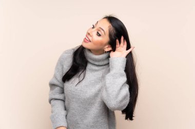 Kolombiyalı genç bir kız izole edilmiş arka planda bir şeyler dinlerken elini kulağına koydu.