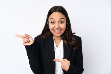 Beyaz arka planda izole edilmiş genç pazarlamacı kadın şaşırmış ve işaret ediyor.