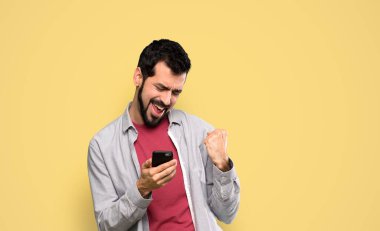 Sakallı, sakallı, sakallı, zafer pozisyonunda, izole edilmiş sarı arka planda.