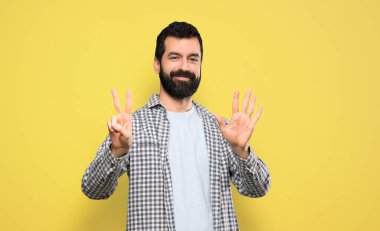 Sakallı yakışıklı adam yediyi parmaklarıyla sayıyor.