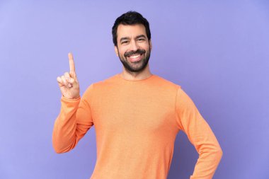 Mor arka planda beyaz tenli yakışıklı adam en iyinin işareti olarak parmağını kaldırıyor ve gösteriyor.