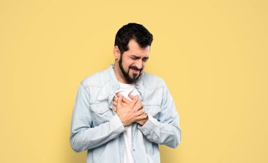 Sakallı yakışıklı bir adamın, izole edilmiş sarı arka planı yüzünden kalbi ağrıyor.