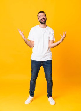 Sakallı, izole edilmiş sarı arka planda gülümseyen uzun boylu bir adam.