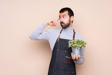 Bir bitkiyi soyutlanmış arka planda tutan adamın şüpheleri ve düşünceleri vardır.