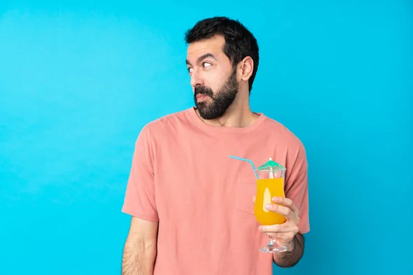 Junger Mann Hält Einen Cocktail Über Einem Isolierten Blauen Hintergrund — Stockfoto