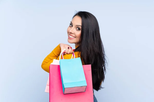 Joven Colombiana Sobre Fondo Azul Aislado Sosteniendo Bolsas Compras Sonriendo —  Fotos de Stock