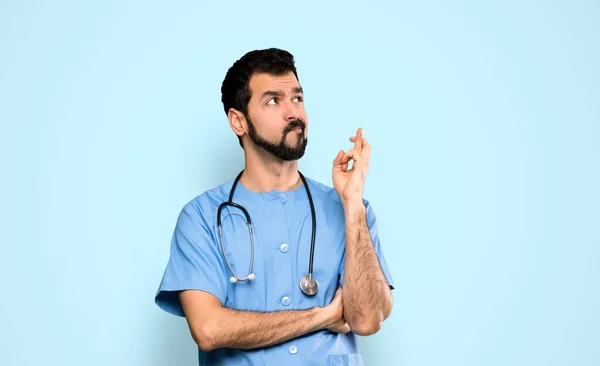 Lekarz Chirurg Człowiek Palcami Skrzyżowania Życząc Wszystkiego Najlepszego Odizolowanym Niebieskim — Zdjęcie stockowe