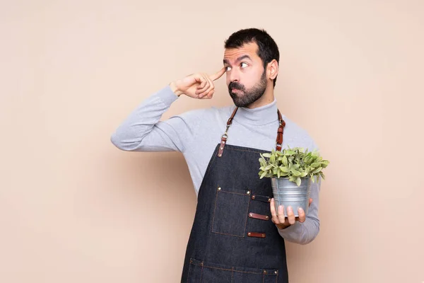 Άντρας Που Κρατάει Ένα Φυτό Απομονωμένο Υπόβαθρο Έχοντας Αμφιβολίες Και — Φωτογραφία Αρχείου