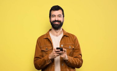 Sakallı yakışıklı adam cep telefonuyla mesaj yolluyor.