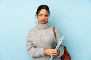 Okula giden melez bir kadın mavi arka planda mahsur kalmış üzgün hissediyor.