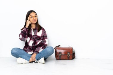 Genç bir bayan öğrenci yerde oturmuş bir fikir düşünüyor.