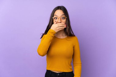 Mor arka planda izole edilmiş genç, melez bir kadın elleriyle ağzını kapatıyor.