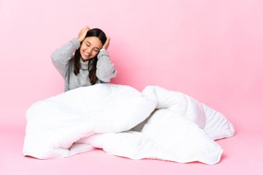 Genç melez kadın pijama giymiş yerde oturmuş gülüyor.