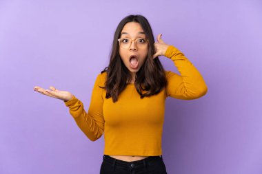 Mor arka planda izole edilmiş genç melez bir kadın telefon jesti yapıyor ve şüpheci