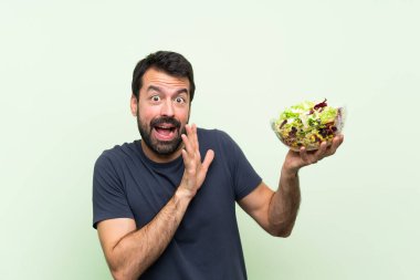 Yeşil duvarın üstünde salatalı yakışıklı genç adam gergin ve korkmuş.