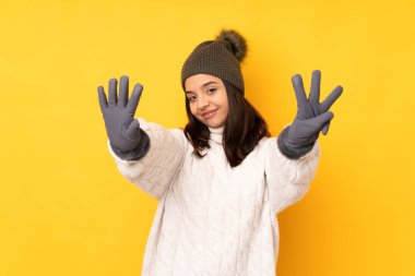 Sarı arka planda, sarı şapkalı genç bir kadın sekiz parmaklı sayıyor.