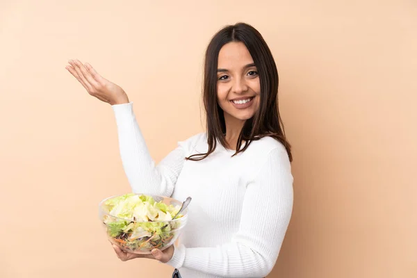 Jovem Morena Segurando Uma Salada Sobre Fundo Isolado Estendendo Mãos — Fotografia de Stock