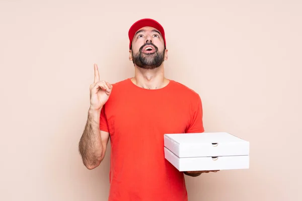 Mladý Muž Drží Pizzu Přes Izolované Pozadí Ukazuje Nahoru Překvapen — Stock fotografie