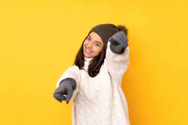 年轻女人戴着冬帽 背对着孤立的黄色背景 微笑着指指点点你 — 图库照片